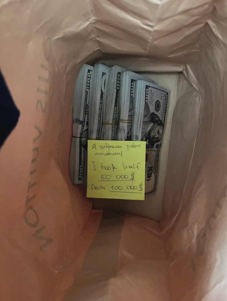 The second photo shows approximately half of the cash removed with a note affixed to the remaining cash written in Cyrillic and English. The English portion of the note reads: &ldquo;I took half 50000$ from 100000$&rdquo;