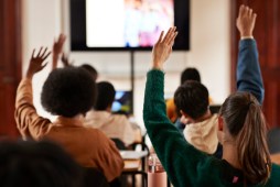 Students with hands raised in classroom.